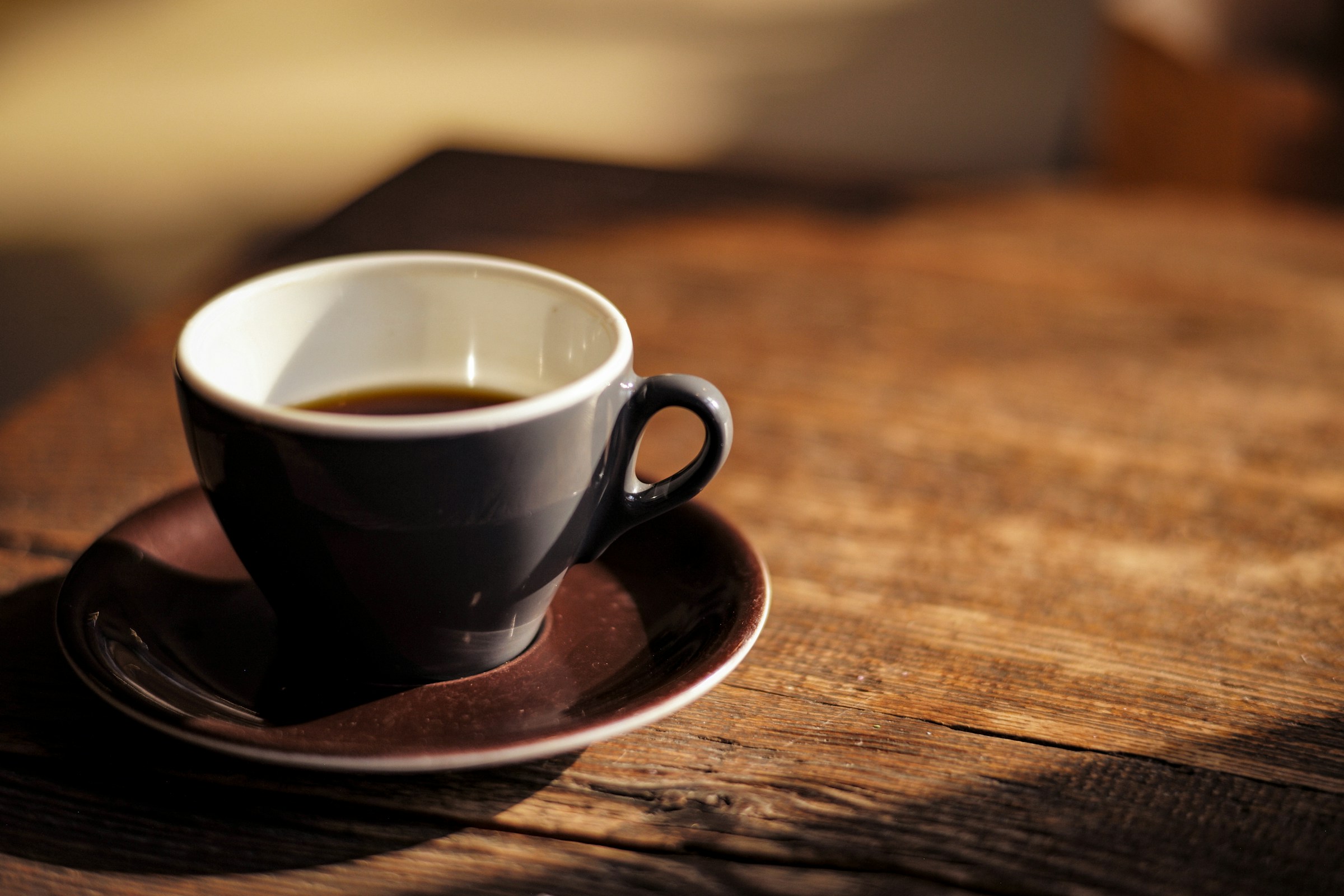 A freshly poured cup of black coffee on a warm wooden table